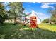 Large backyard featuring a swing set and playground, along with a partially covered deck and manicured lawn at 10401 Monarch Ct, Noblesville, IN 46060