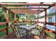 Outdoor deck with a pergola-style roof, furnished with a glass table and colorful chairs overlooking the backyard at 10401 Monarch Ct, Noblesville, IN 46060