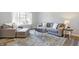 Cozy living room with gray sofa, chair and ottoman, a decorative rug, and lots of natural light at 10401 Monarch Ct, Noblesville, IN 46060