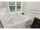 Relaxing bathroom with a garden tub, granite countertop, and white tile with a black accent stripe at 11974 Volcanic Rock Dr, Fishers, IN 46037