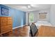 Cozy bedroom with hardwood floors, a wooden dresser, an accent wall, and a bright window at 11974 Volcanic Rock Dr, Fishers, IN 46037