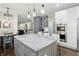 Open kitchen with gray island, modern lighting, stainless appliances and view to dining and living areas at 11974 Volcanic Rock Dr, Fishers, IN 46037