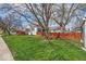 Well-maintained front yard with a large shade tree, red fence, and a charming house with a deck at 1441 N Euclid Ave, Indianapolis, IN 46201