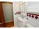 Neat bathroom with a vanity, toilet, and decorative tile accents, next to a doorway leading to another room at 218 Demarest Dr, Indianapolis, IN 46214