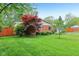Green lawn with mature trees create a serene setting for the charming single-story brick home at 2910 S Sheridan Ave, Indianapolis, IN 46203