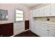 Kitchen area featuring white cabinets, tiled backsplash, and exterior door at 3015 E Sumner Ave, Indianapolis, IN 46237