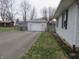 Detached one-car garage with white siding and a single door, adjacent to a paved driveway and lawn at 406 W Jackson St, Alexandria, IN 46001