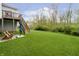 Spacious backyard with green lawn, a wooden deck with seating, and lush landscaping at 4196 Parliament Way, Avon, IN 46123