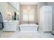 Luxurious bathroom with white tub, large window, decorative lighting and white cabinets at 4258 Hamilton Run, Zionsville, IN 46077