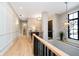 Upstairs hallway featuring hardwood floors, panelled walls, and modern geometric light fixtures at 4258 Hamilton Run, Zionsville, IN 46077