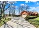 Brick ranch-style house with an attached garage and a long driveway surrounded by mature trees and greenery at 4263 W Fox Ridge Ave, Greenwood, IN 46143