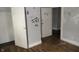 Empty room featuring two open door frames, graffiti on the walls, and dark wood floors at 4925 E New York St, Indianapolis, IN 46201