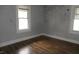 Empty room featuring two windows, blue walls with graffiti, and dark wood flooring at 4925 E New York St, Indianapolis, IN 46201