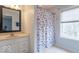 Bright bathroom featuring a vanity with drawers, mirror, floral shower curtain, and large window at 633 Foxboro Dr, Avon, IN 46123