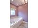 Bathroom featuring a luxurious soaking tub beneath a chandelier and large window at 633 Foxboro Dr, Avon, IN 46123