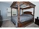 Inviting main bedroom featuring a carved four-poster bed with a gray comforter and large window at 7527 Derek Dr, Camby, IN 46113