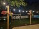 Backyard with a playset, swing, and string lights, enhanced with colorful hanging flower baskets on posts at 7809 Bryden Dr, Fishers, IN 46038