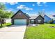 Charming brick home featuring an attached garage, well-manicured lawn, and inviting curb appeal at 8807 Wintergreen Way, Indianapolis, IN 46256