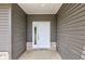 View of the white front door with glass panes and gray siding on a covered front porch at 9182 Mulligan Ct, Elwood, IN 46036