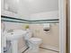 Bathroom with pedestal sink, toilet, and decorative green tile trim at 1025 E 60Th St, Indianapolis, IN 46220