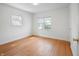 Bright bedroom with hardwood floors, two windows, and a door leading into the hallway at 1025 E 60Th St, Indianapolis, IN 46220