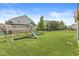 Expansive backyard with lush green grass, a playset, and a secure black fence, perfect for outdoor activities at 11003 Liberation Trce, Noblesville, IN 46060