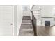 Carpeted staircase with wood railing leading to the open living area with a fireplace at 11003 Liberation Trce, Noblesville, IN 46060