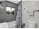 Contemporary bathroom with gray tiling, a shower-tub combo, and natural light filtering through the window at 1139 E 35Th St, Indianapolis, IN 46205