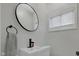 Modern half bathroom with white fixtures, black hardware, and a round mirror at 1139 E 35Th St, Indianapolis, IN 46205
