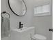 Modern half bathroom with white fixtures, black hardware, and a round mirror at 1139 E 35Th St, Indianapolis, IN 46205