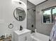 Stylish bathroom with a modern vanity, round mirror, and a combined shower-tub, creating a serene space at 1139 E 35Th St, Indianapolis, IN 46205