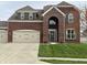 Elegant brick home featuring a prominent arched entryway, three-car garage, and lush green lawn at 11958 Logan Hunter Trl, Noblesville, IN 46060