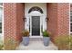 Close up of the home's elegant front door with a brick facade, decorative planters, and classic lighting fixtures at 12030 Auburn Creek, Zionsville, IN 46077