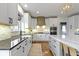 Modern kitchen with marble countertops, stainless appliances, white cabinetry, and a stylish wooden range hood at 12030 Auburn Creek, Zionsville, IN 46077