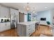 Open kitchen with white cabinets, stainless steel appliances, large island with seating, and hardwood floors at 12030 Auburn Creek, Zionsville, IN 46077