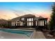 A dusk view of a brick home with a luxurious pool, deck, and outdoor kitchen at 13214 Mink Ln, Carmel, IN 46074