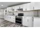 Modern kitchen featuring stainless steel appliances, white cabinets, gray counter tops, and gray wood flooring at 1331 W 33Rd St, Indianapolis, IN 46208
