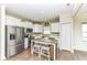 Cozy kitchen with stainless steel appliances, white cabinetry, laminate floor, and eat-in island with stools at 1455 Bigleaf Dr, Sheridan, IN 46069
