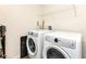 Functional laundry room with white front-loading washer and dryer, storage shelf, and ample space at 1455 Bigleaf Dr, Sheridan, IN 46069