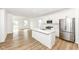 Open kitchen with white cabinets, stainless steel appliances, a kitchen island, and wood-look floors at 159 Derringer Ave, Westfield, IN 46074
