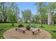 Backyard fire pit with wooden benches and blue chairs surrounded by trees at 1901 S Old State Road 67, Paragon, IN 46166