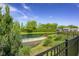 Beautiful pond view with mature trees and serene landscaping, seen through a black metal fence at 2736 Victory Dr, Columbus, IN 47203