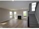 Spacious living room with fireplace, natural light, and hardwood floors, and black staircase at 4960 Cinnabar Trl, Brownsburg, IN 46112