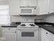 A kitchen with white appliances and cabinets with black countertops at 5512 Straw Hat Dr, Indianapolis, IN 46237