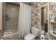 Modern bathroom with floral wallpaper, tub and toilet, illuminated by natural light at 5973 Masten Rd, Coatesville, IN 46121