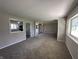 Bright living room featuring neutral carpet and views into the kitchen and other living spaces at 6672 E 225 S, Whitestown, IN 46075