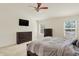 Well-lit bedroom with a large window, dark furniture, ceiling fan, and mounted TV at 6869 W Winding, McCordsville, IN 46055
