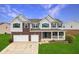 Charming two-story house featuring a brick facade, covered porch, and attached two-car garage at 7048 Millet Ln, Avon, IN 46123