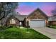 Beautiful brick home with manicured lawn, flowering tree, and two-car garage at dusk at 7242 River Glen Dr, Fishers, IN 46038