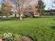Sprawling backyard with manicured lawn, mature trees, and landscaping for outdoor enjoyment at 7664 Lincoln Trl, Plainfield, IN 46168